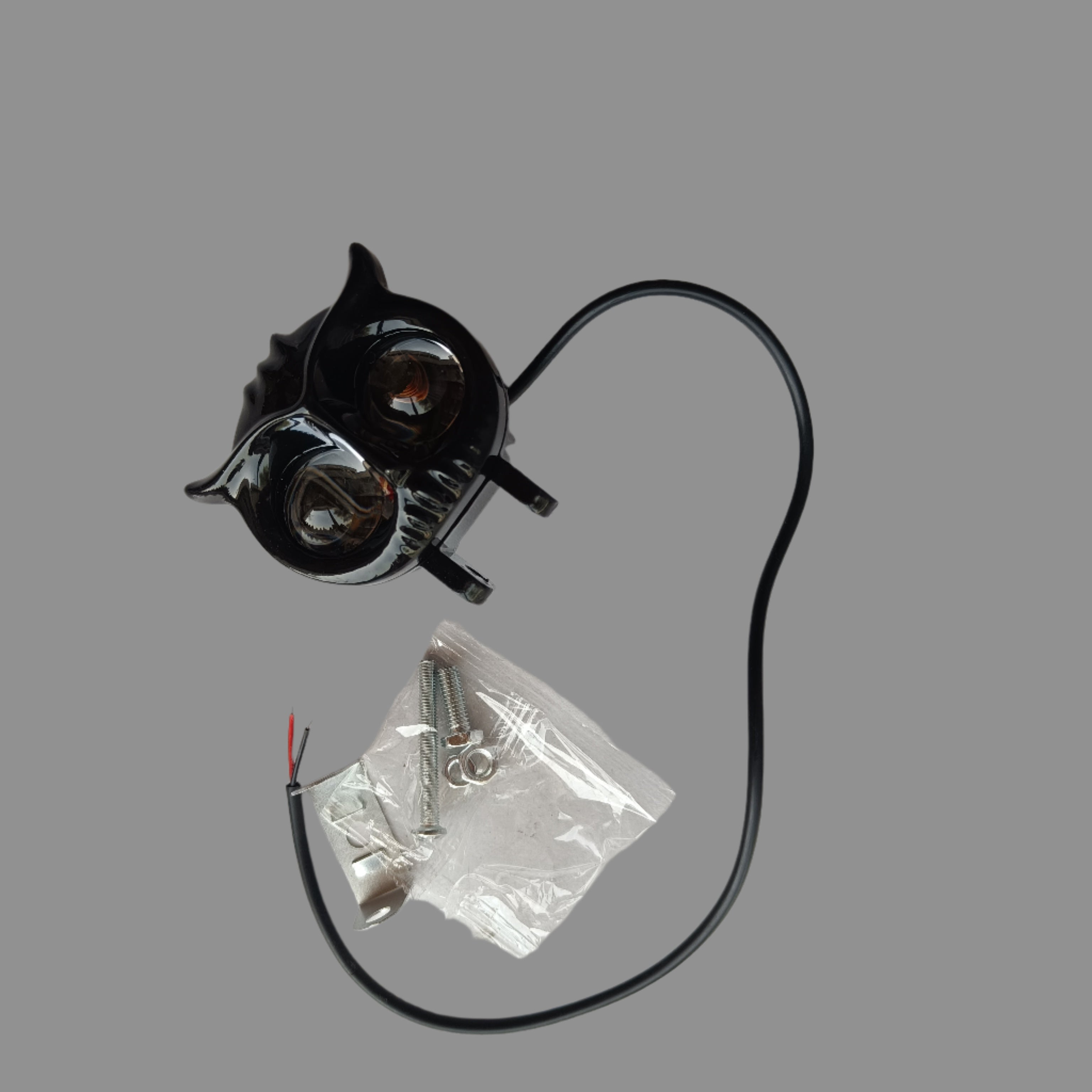 Small metal component with a black cord on a white surface